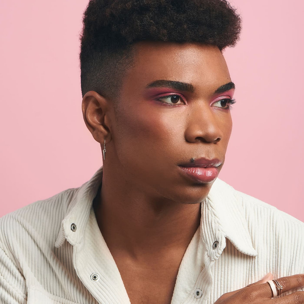Man wearing editorial style makeup on pink background