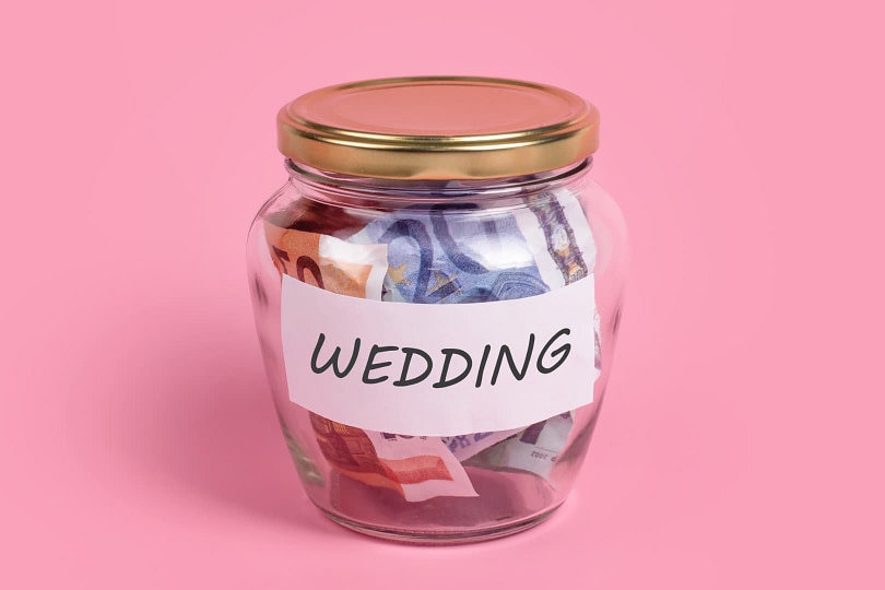 A jar filled with money with the label wedding on the front