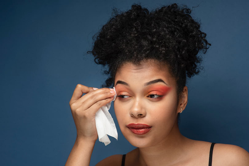 Beautiful woman removing her eye makeup with a removal wipe