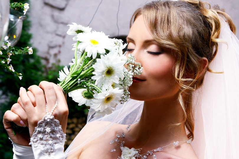 Bride outside smelling a bouquet of flowers