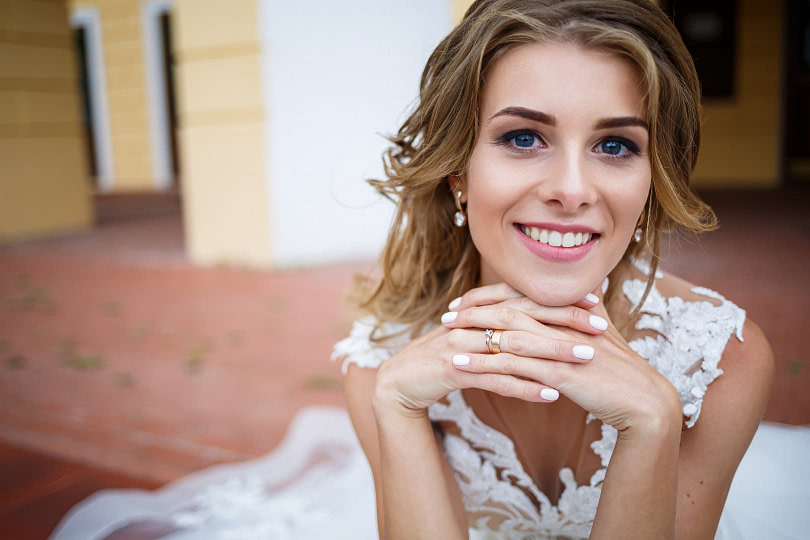 Happy bride posing outside in wedding dress with beautiful bridal makeup