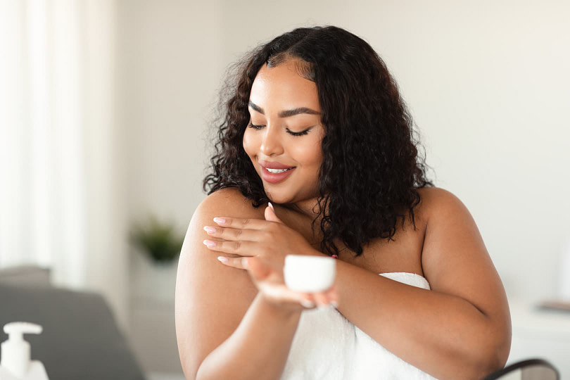 Woman putting on skincare products as she's getting ready in the morning